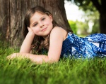 Photo of girl lying down in front of tree.